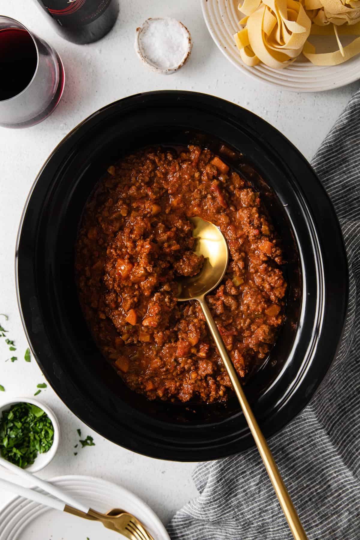 slow cooker bolognese sauce in the slow cooker with a spoon