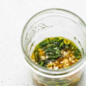 A glass jar filled with a mixture of herbs and spices.