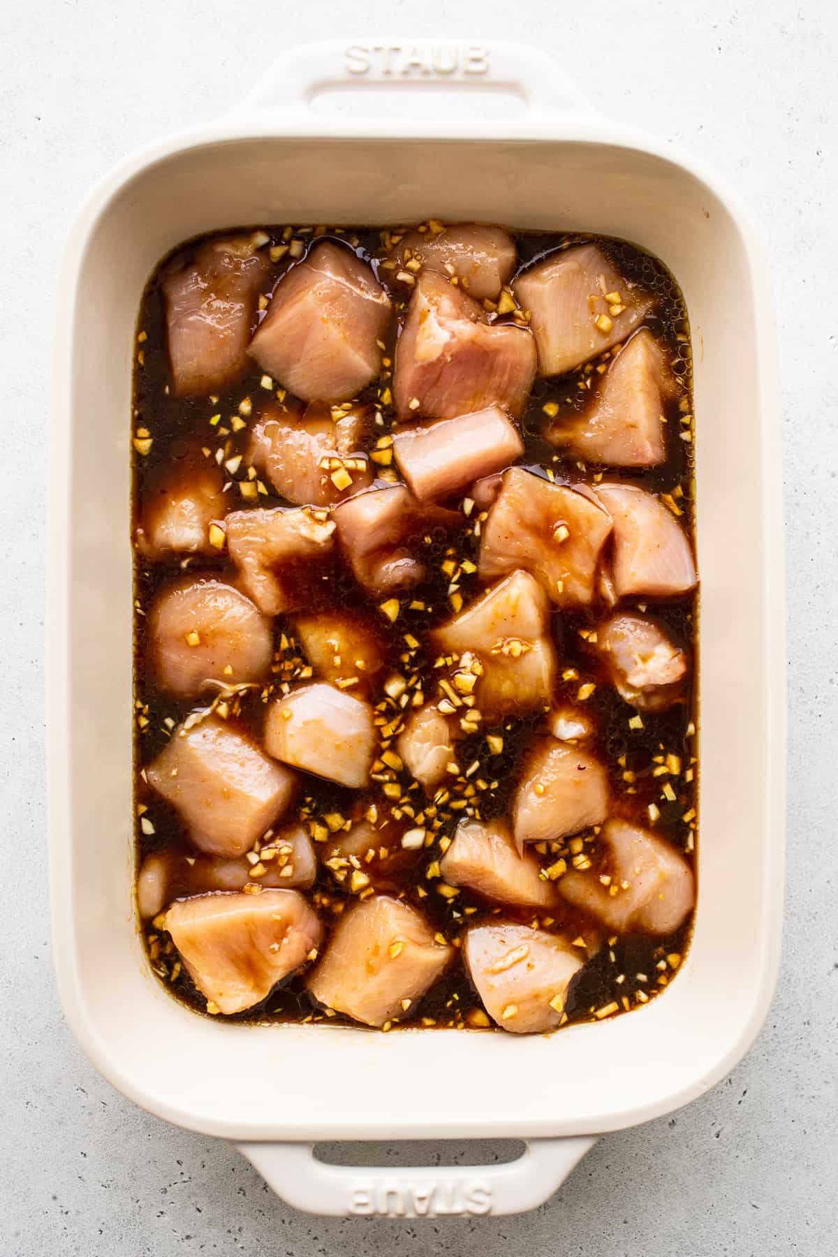 Chicken marinating in dish.