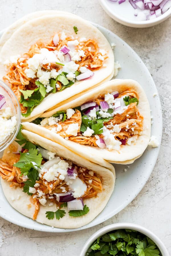 Three chicken tacos on a white plate.