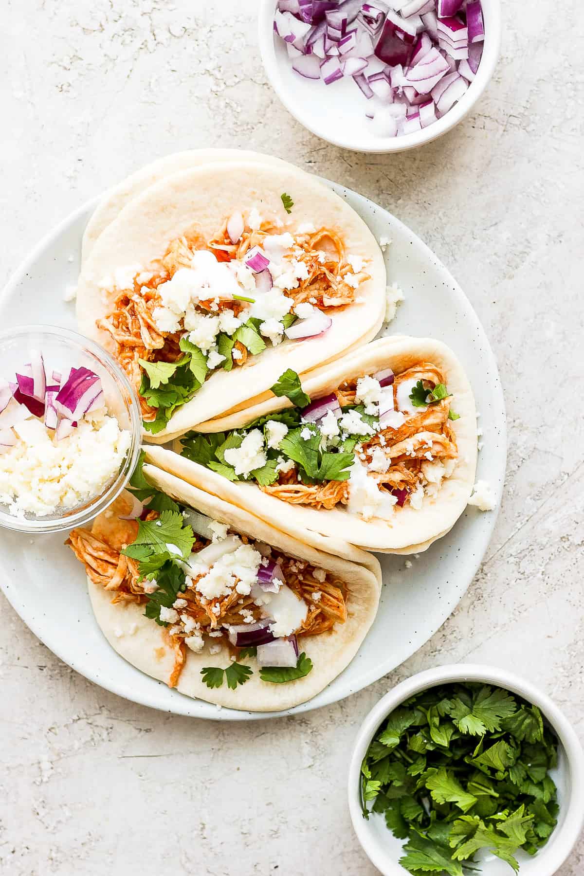 Three chicken tinga tacos on a plate. 