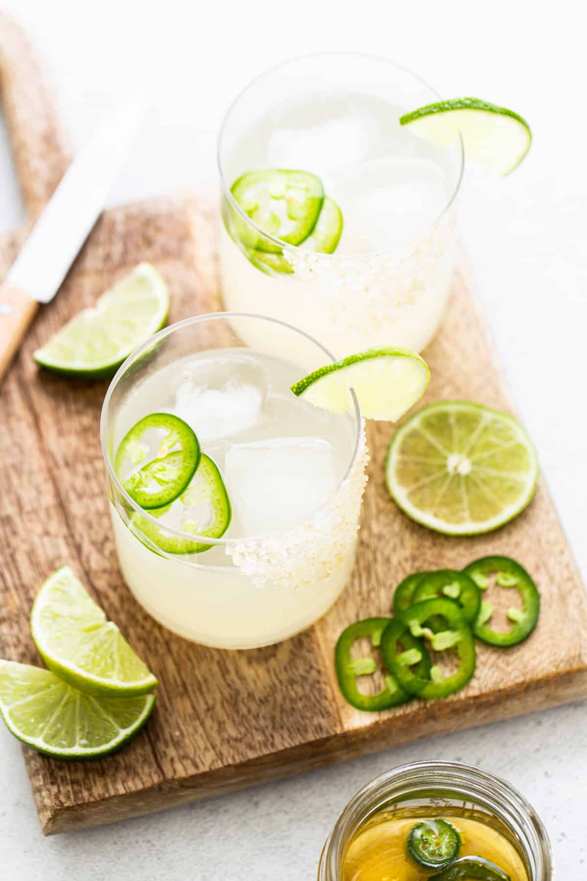 Two spicy mezcal margaritas on a cutting board.