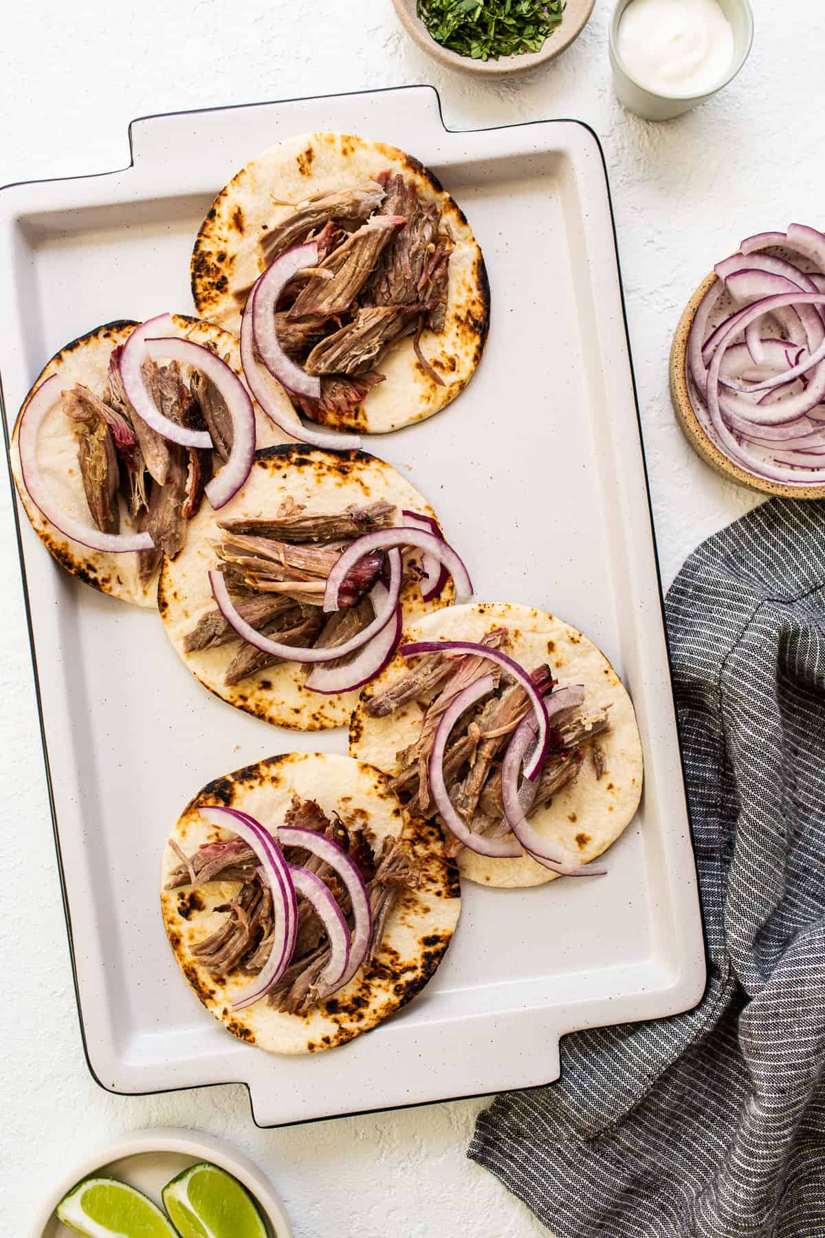 tortillas with shredded pork and sliced onion on top.