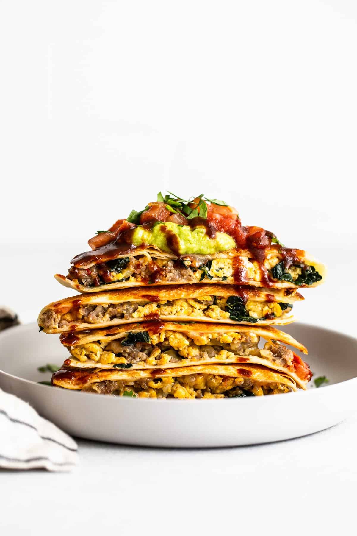 Slices of breakfast quesadillas stacked on a plate.