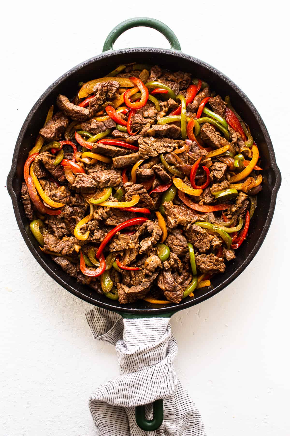 Steak fajitas and fajita veggies in a cast iron skillet.