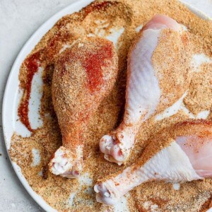 A plate with grilled chicken legs seasoned and served in a white dish.