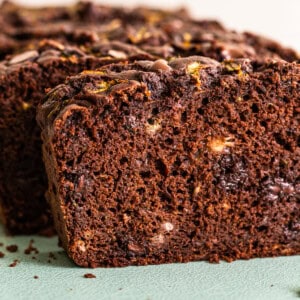 A slice of chocolate zucchini bread on a green cutting board.