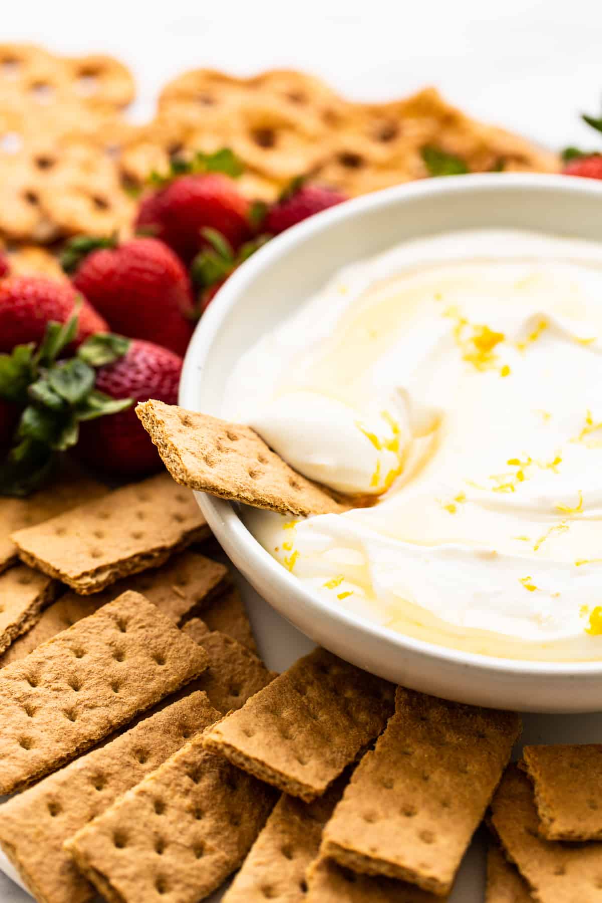 Fruit dip with a graham cracker dipped into it.