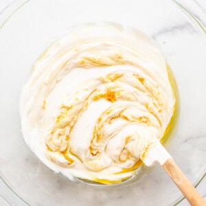 Whipped cream in a bowl with a wooden spoon.