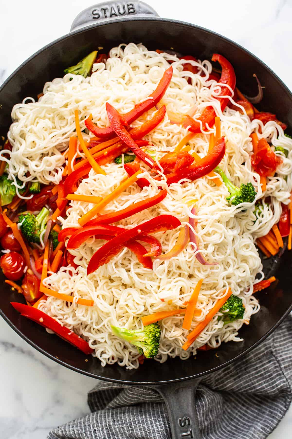 Mixing noodles with veggies.