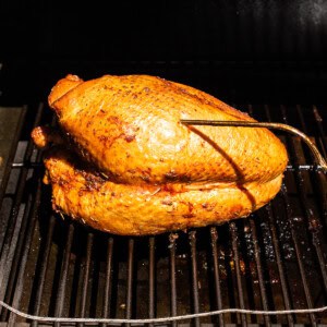 A turkey breast smoking on a smoker.