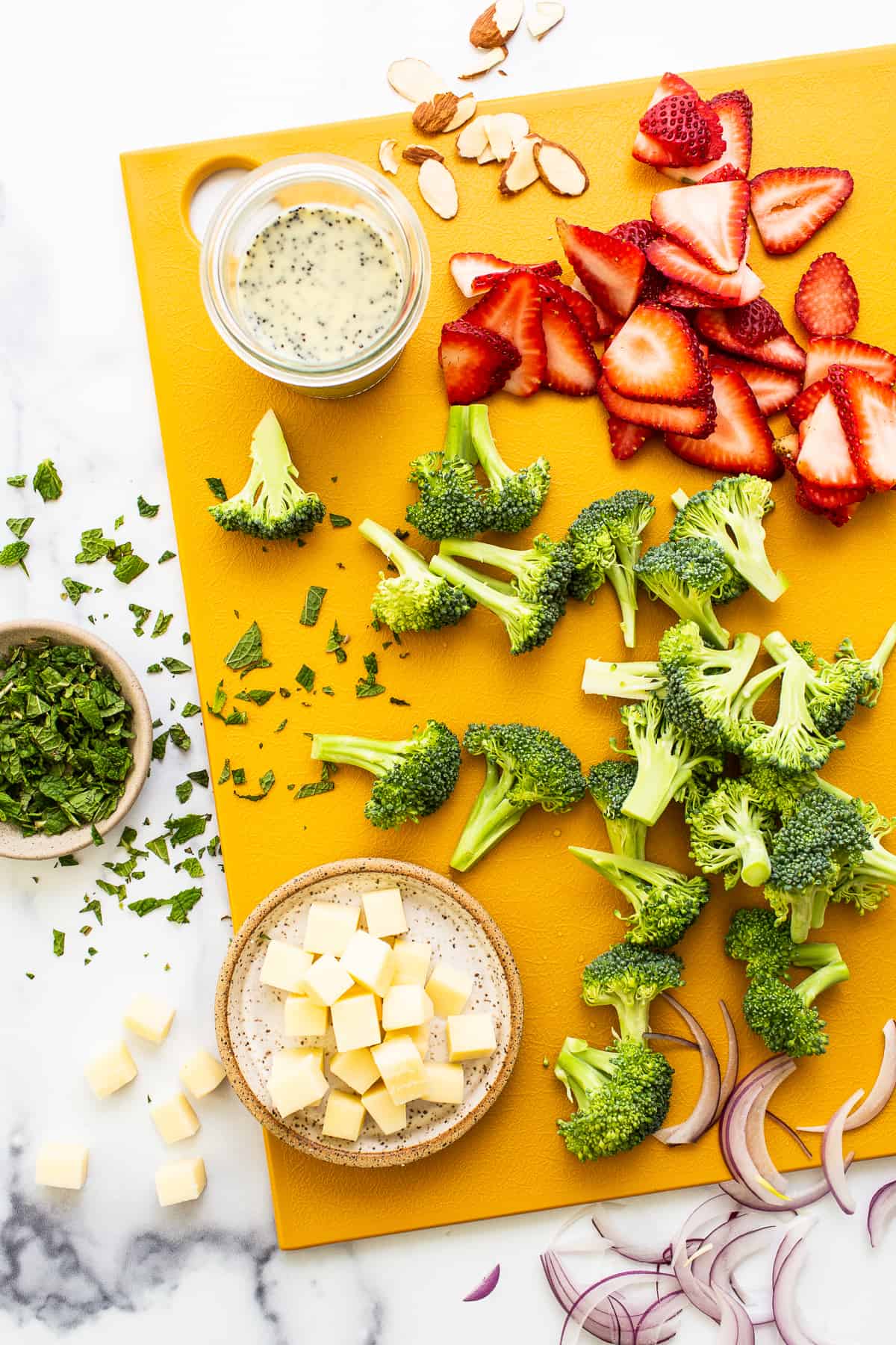 Ingredients for strawberry broccoli salad on a cutting board.