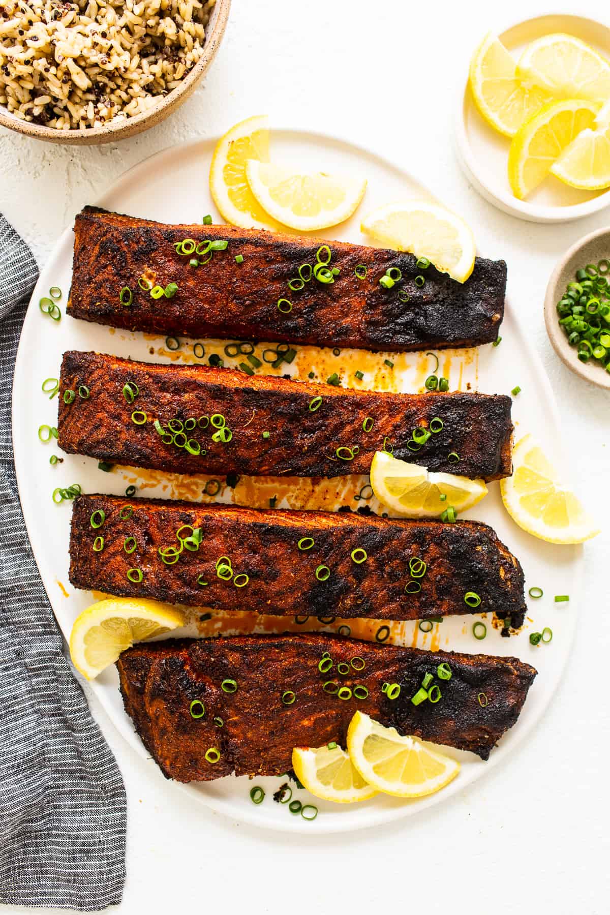 Blackened salmon on a plate with lemon slices. 