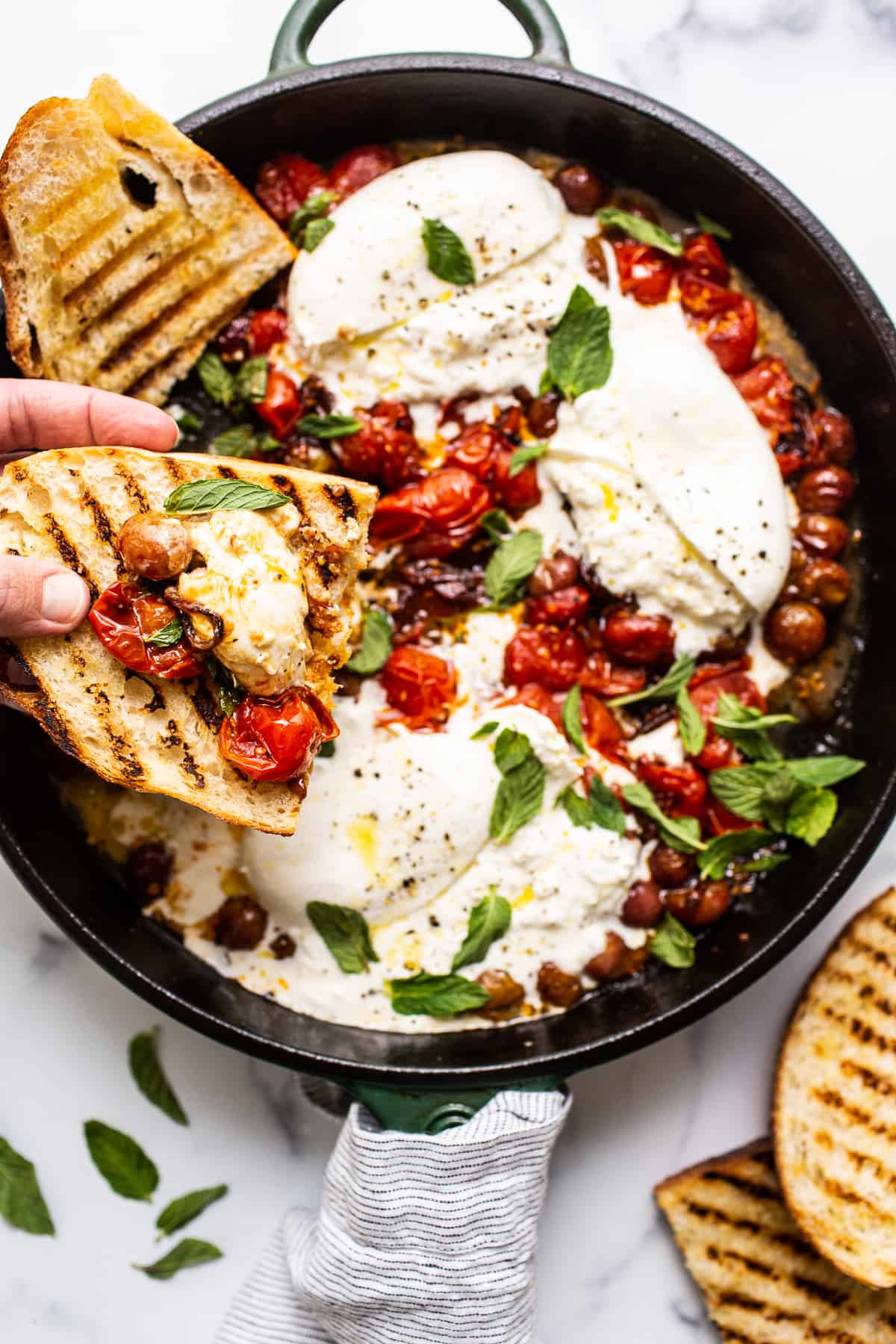 toasted bread scooping burrata cheese and tomatoes.