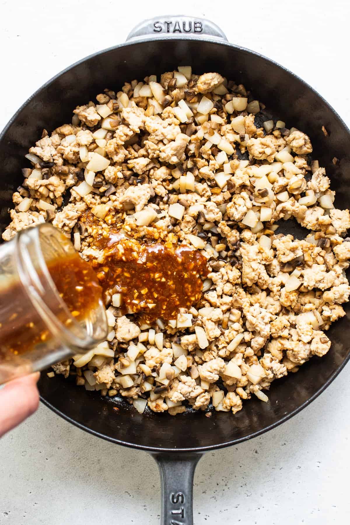 pouring sauce onto ground chicken.