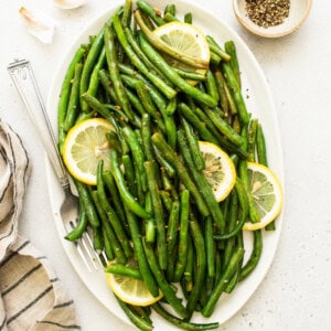 cooked green beans and lemon on platter.