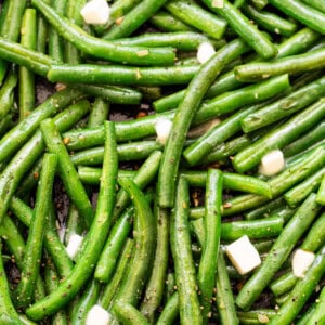 A pan with green beans and cheese on it.