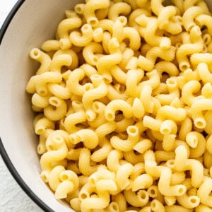 Macaroni in a bowl on a white surface.