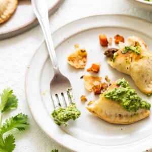 Empanadas with green sauce on top.