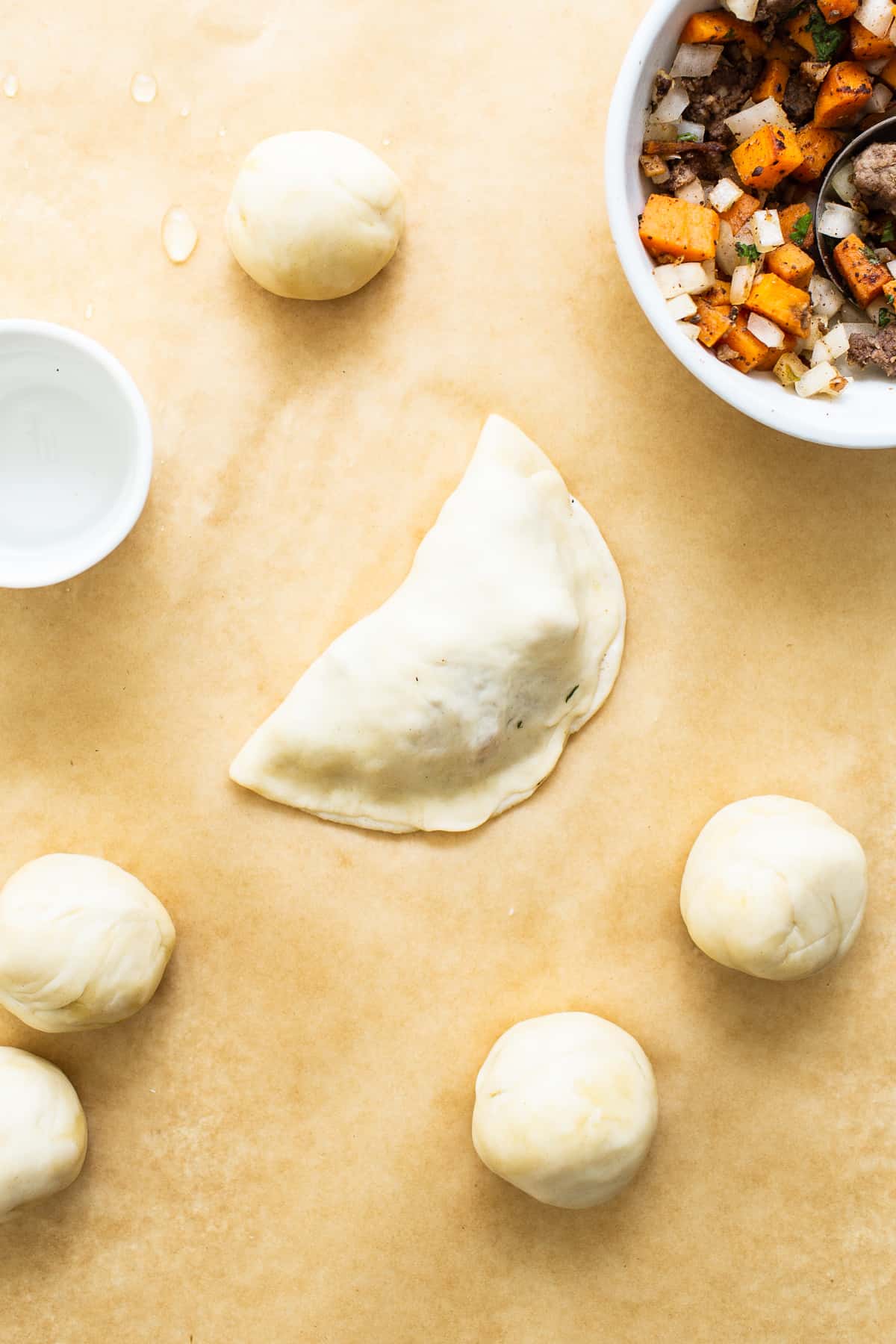 Sweet Potato Ground Beef Empanadas on parchment paper before baking.