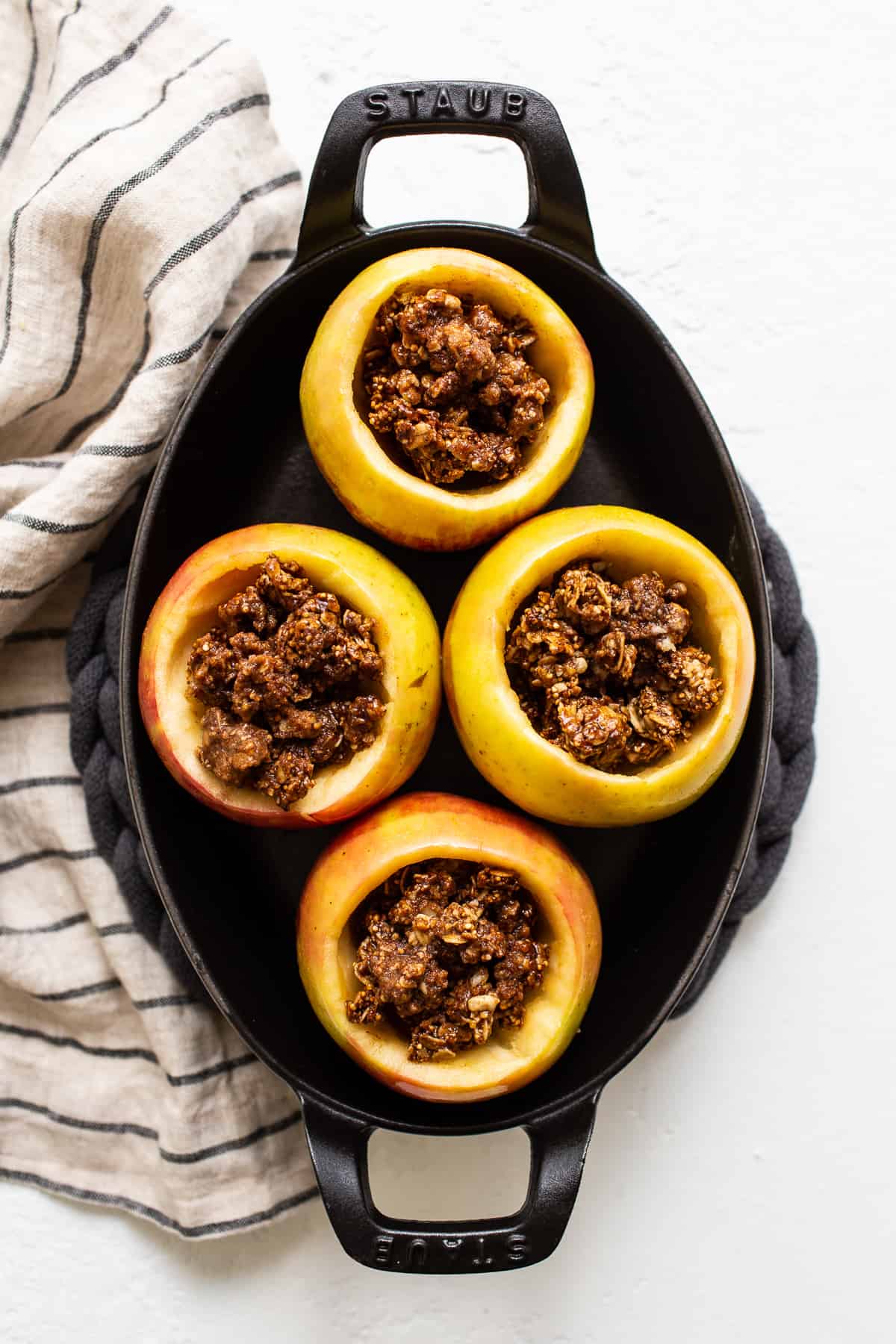 Apples filled with streusel in a baking dish.