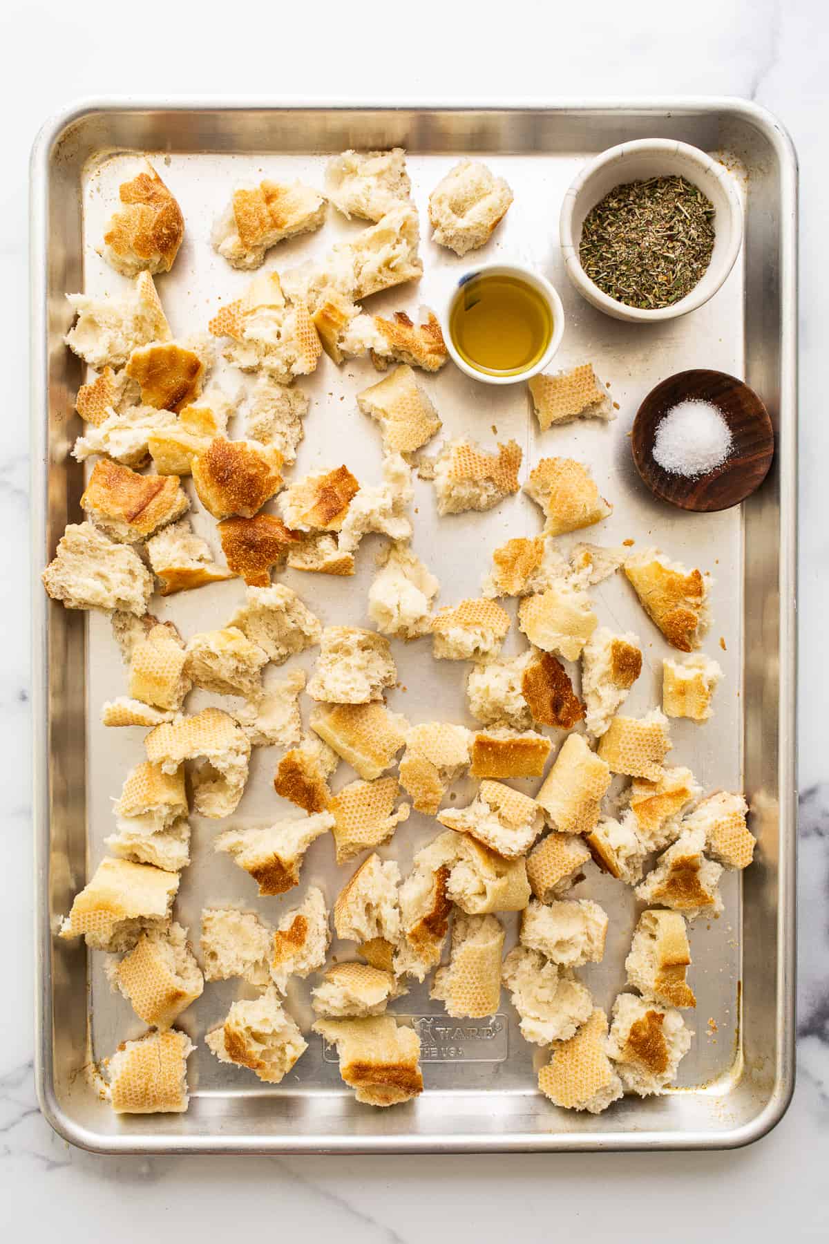 pieces of bread and spices on a baking sheet.