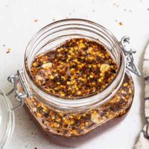 A jar of chili sauce with a spoon and a napkin.