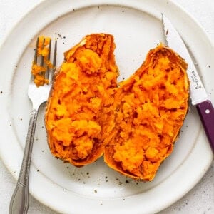 A sweet potato cut in half on a plate.