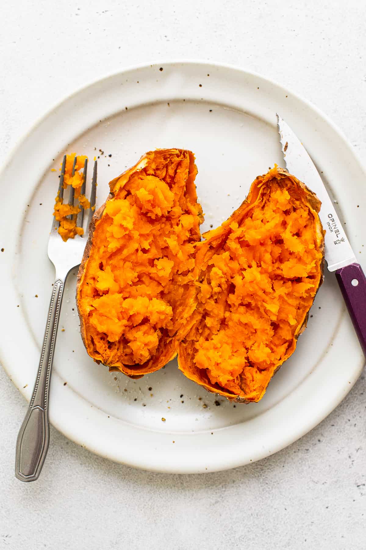 A sweet potato cut in half on a plate.