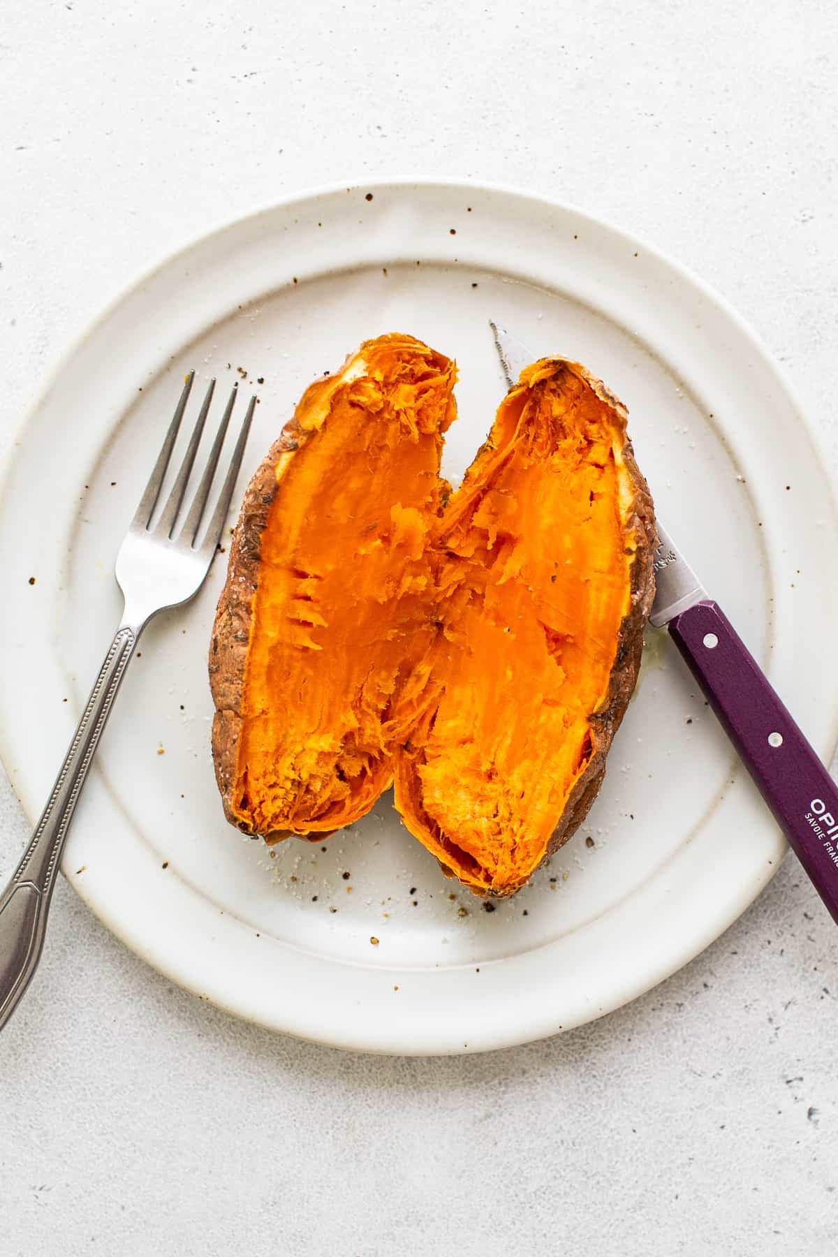 A sweet potato cut in half on a plate.