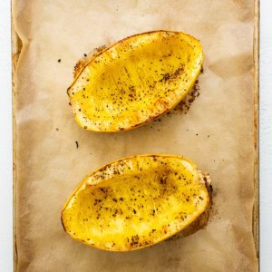 Two slices of baked sweet potato on a baking sheet.