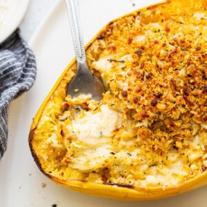 A yellow squash casserole with a spoon on a plate.