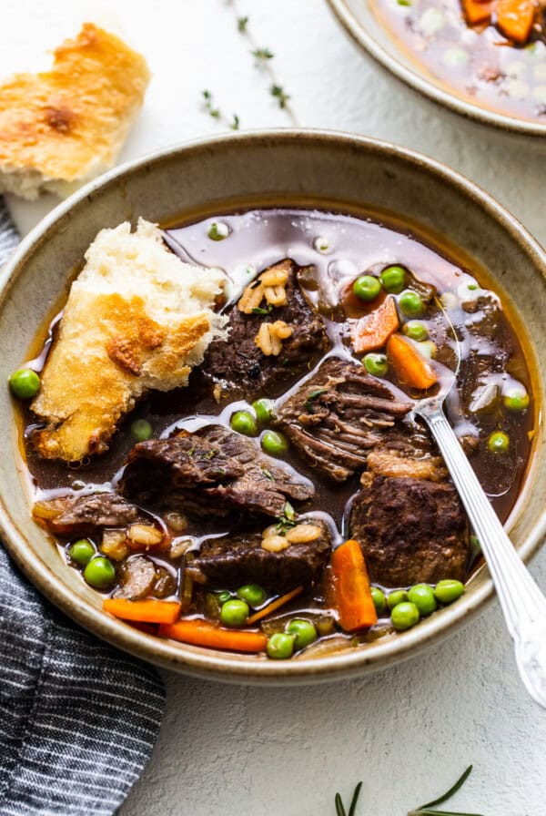 beef and barley soup in bowl with spoon.