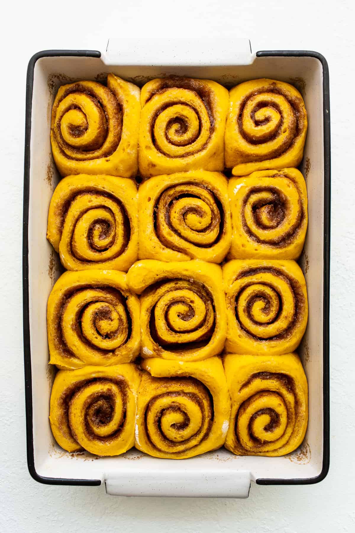 Pumpkin cinnamon rolls in a baking dish.