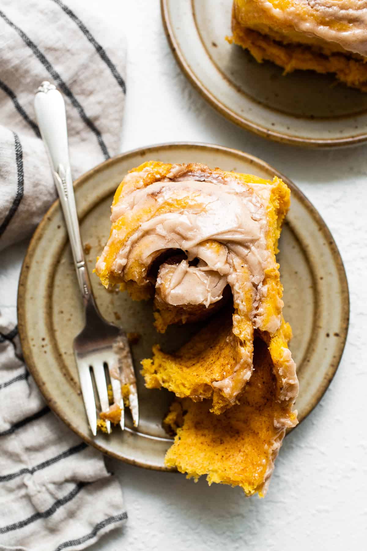 Pumpkin cinnamon roll on a plate with a fork.