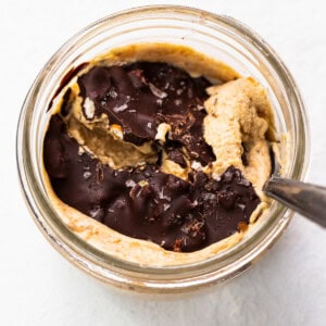 Peanut butter in a glass bowl with a spoon.