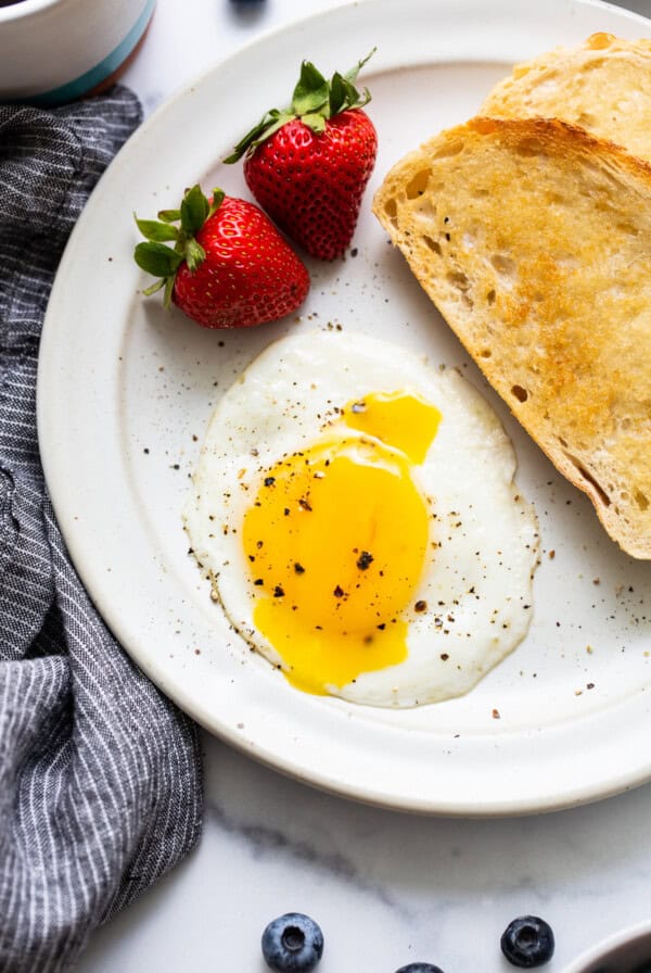 Sunny side up egg on a plate with toast.