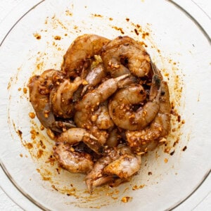 Shrimp in a glass bowl on a white surface.