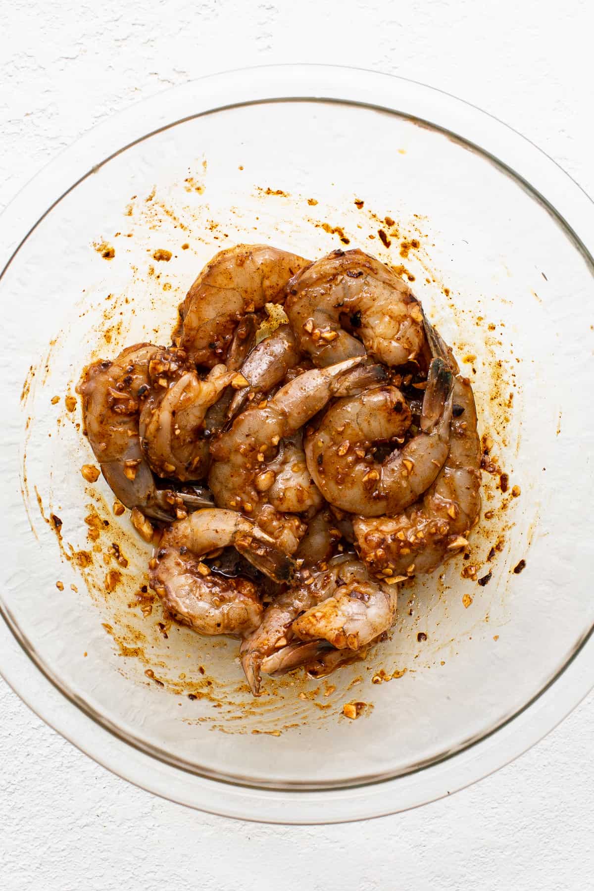 Raw shrimp in a bowl with a marinade.