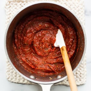 Tomato sauce in a pan with a wooden spoon.