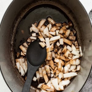 A pot with onions in it and a black spoon.