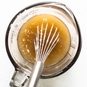 A whisk in a bowl with a liquid in it.