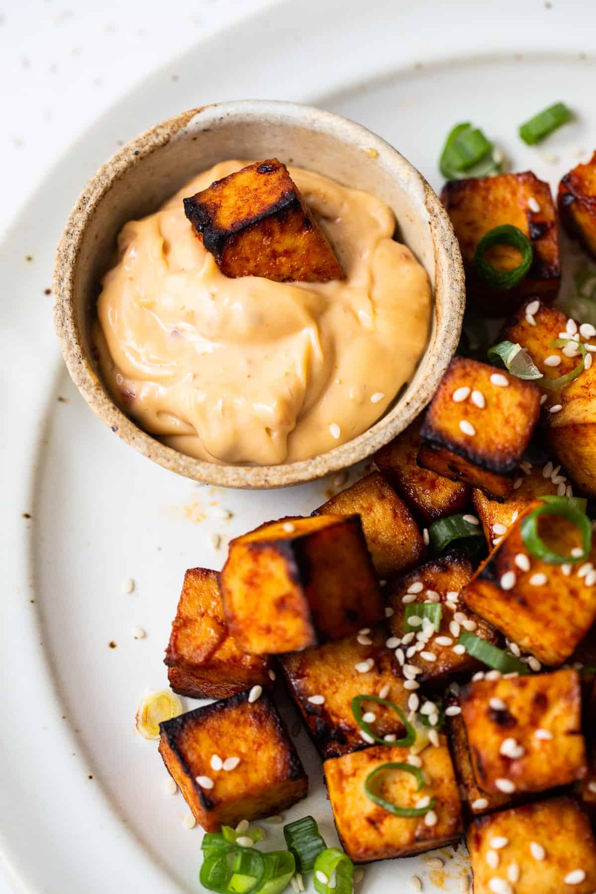 A piece of tofu in a spicy dipping sauce. 