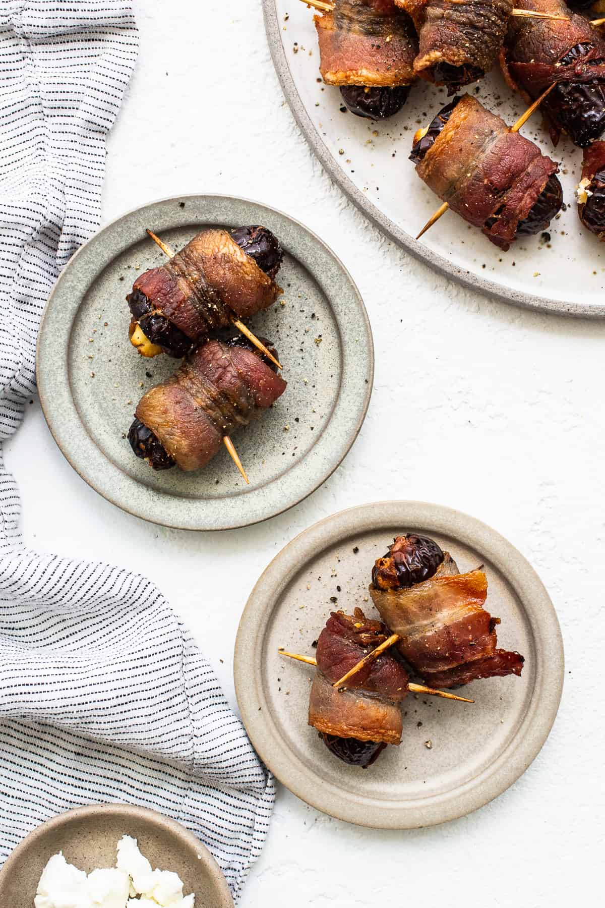 Bacon wrapped dates with goat cheese on a plate.