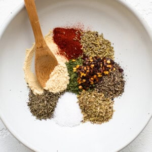 Spices in a white bowl with a wooden spoon.