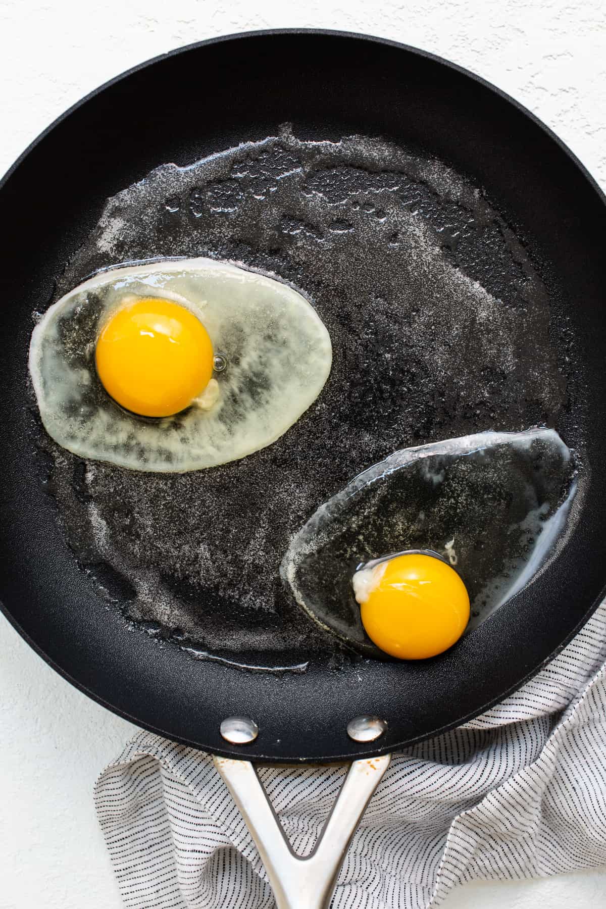 Over hard eggs cooking in a skillet.