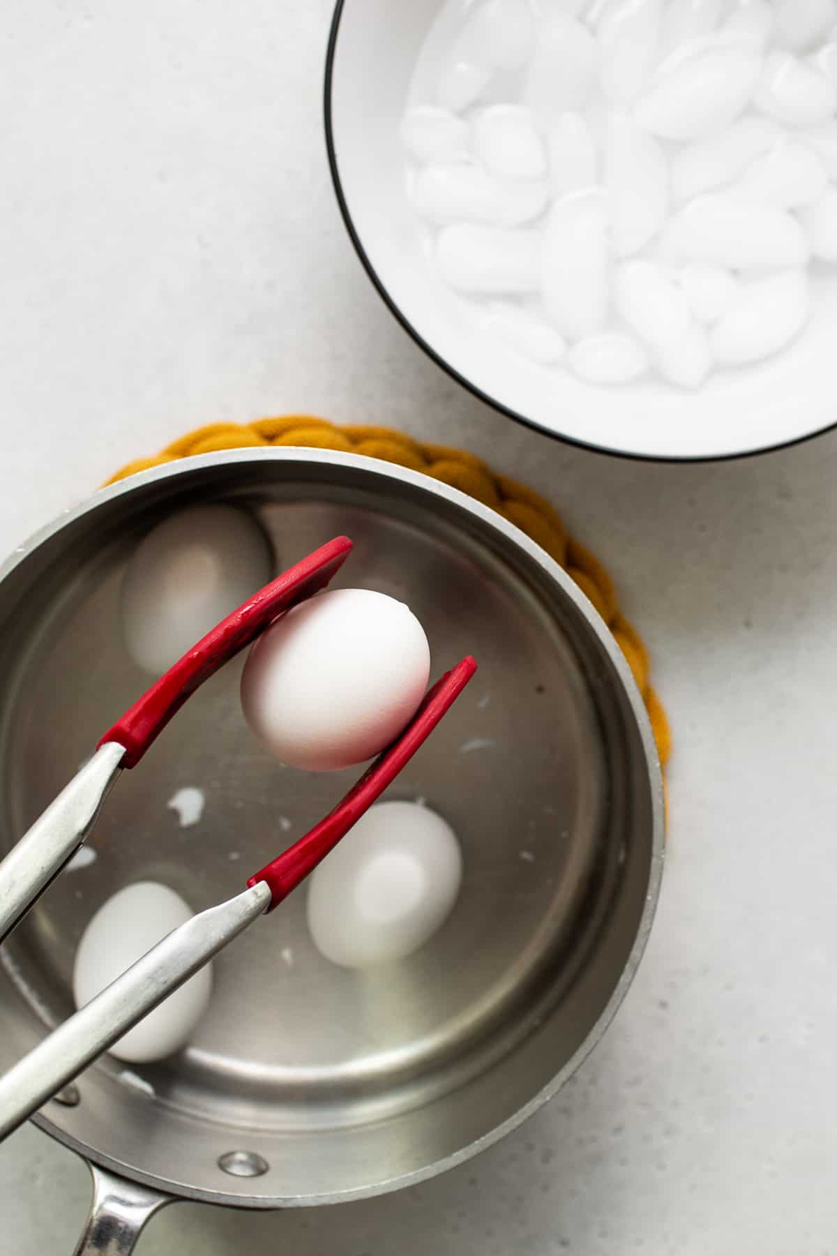 Soft boiled egg being held with a set of tongs.