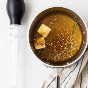 A pot of soup with a spoon and a measuring spoon.