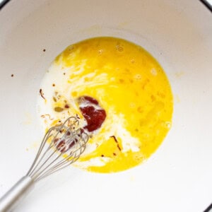 An egg in a bowl with a whisk.