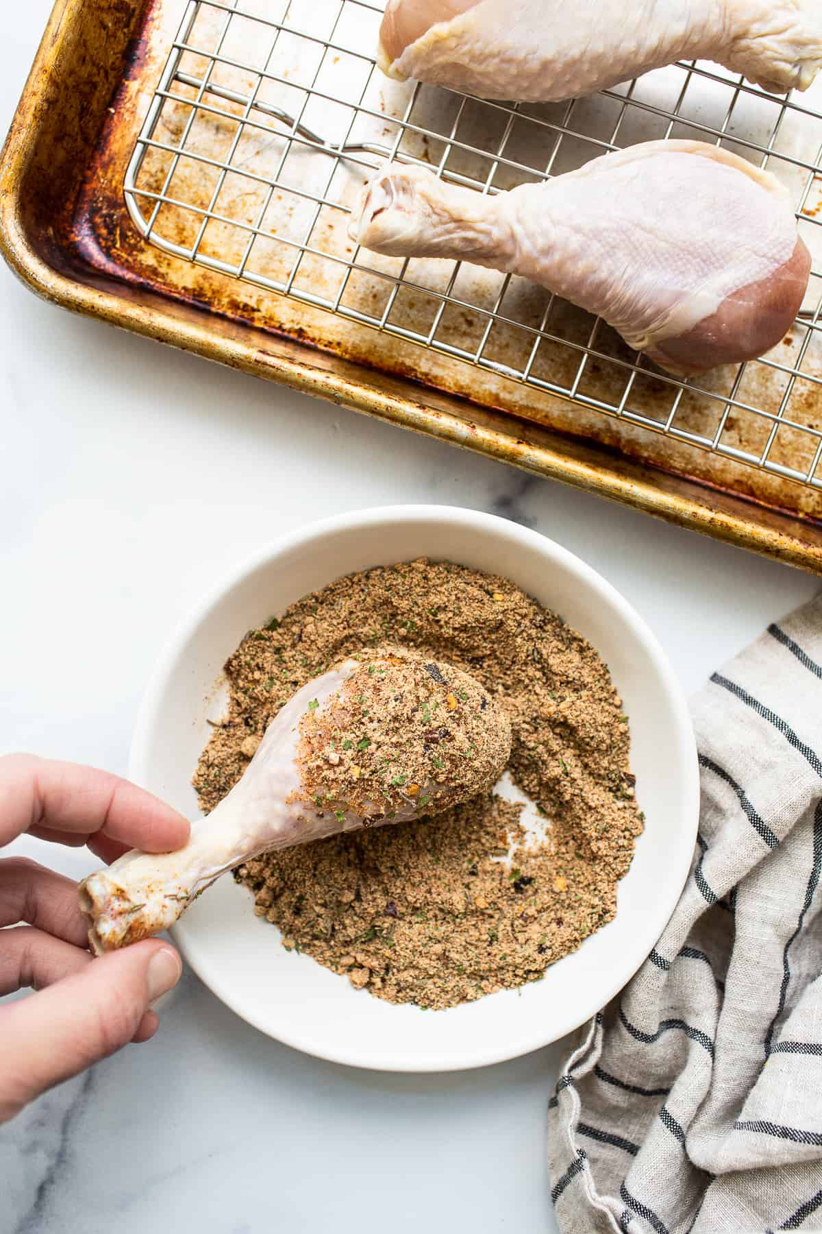 Chicken legs being rolled in chicken seasoning.